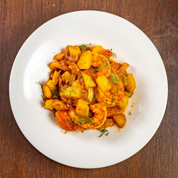 Shrimp and potato dish with fresh dill on a white plate at Bistro Casa Azul.