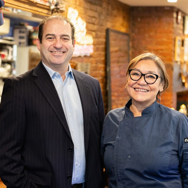 Bistro Casa Azul owners, a man in a suit and a woman in a chef's coat, smiling.