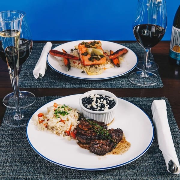 Two plates of Mexican cuisine, one with steak and rice, the other with salmon and rice.